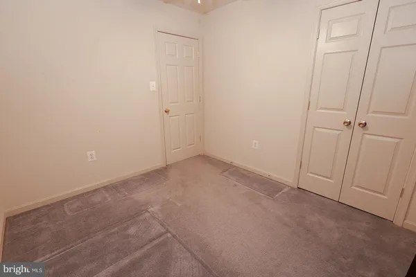 an empty room with windows and a chandelier fan