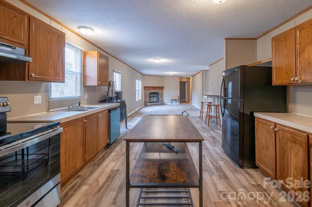 a kitchen with stainless steel appliances granite countertop a refrigerator a stove and a sink with wooden cabinets