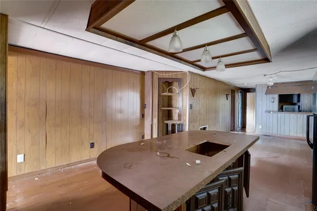 a view of kitchen island with a sink stainless steel appliances wooden floor and a window