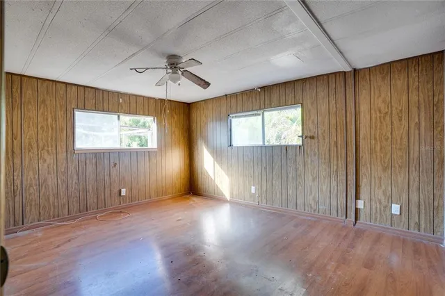 an empty room with windows and ceiling fan