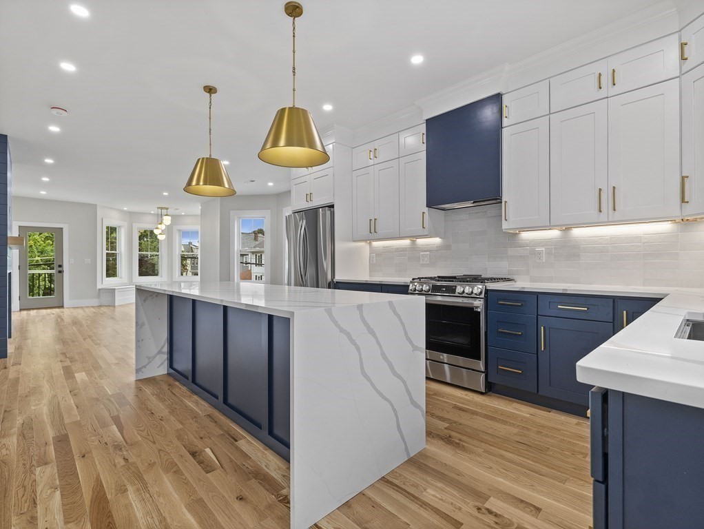 a kitchen with stainless steel appliances kitchen island granite countertop a stove a sink and a wooden cabinets