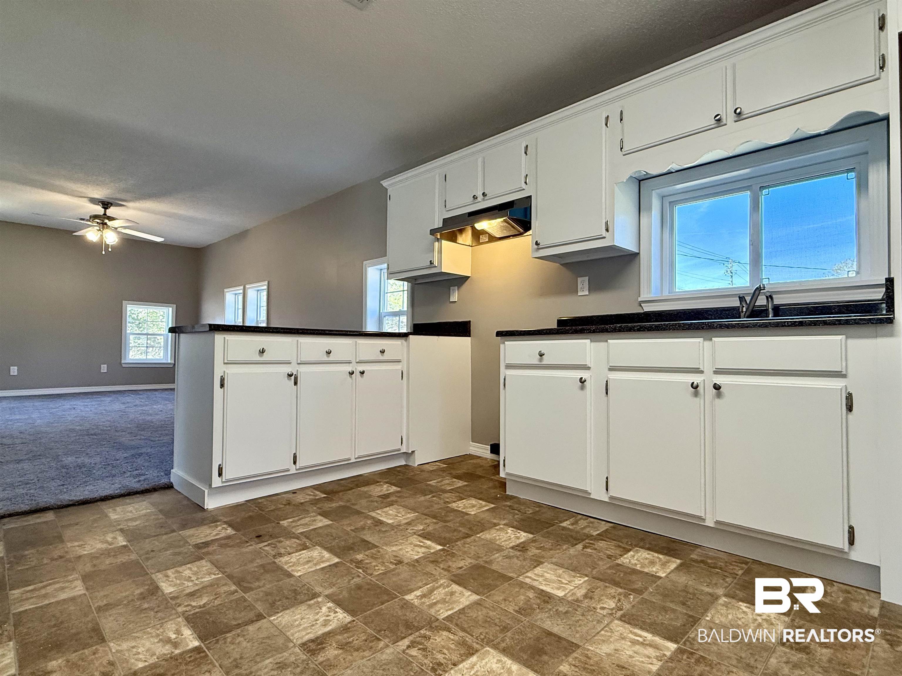 205 Schad Street Brewton, AL 36426 - Photo 6 of 11 Kitchen featuring white cabinets, healthy amount of natural light, stone finish floors, and a peninsula