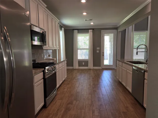 a large kitchen with a center island wooden floor stainless steel appliances and windows
