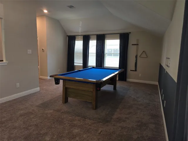 a room with pool table and windows