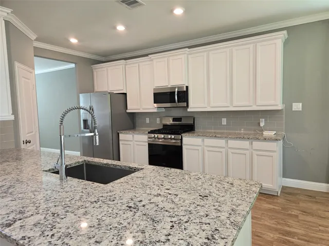 a kitchen with granite countertop a refrigerator sink and microwave