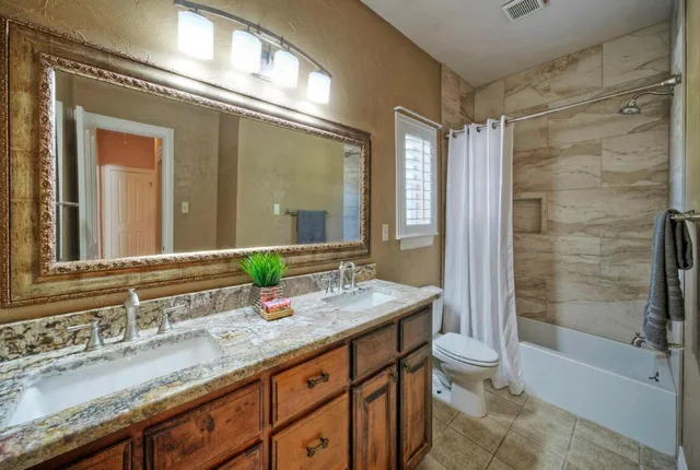 a bathroom with a granite countertop sink mirror toilet and bathtub