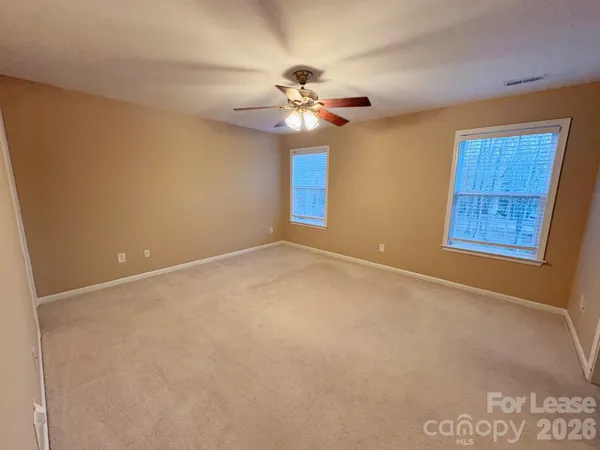 an empty room with windows and fan