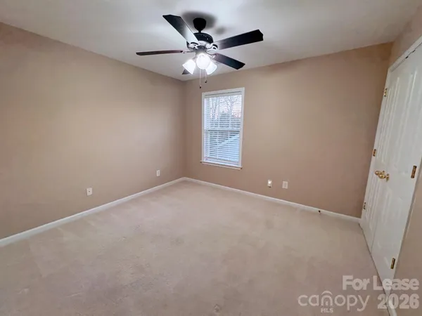 an empty room with a ceiling fan and window