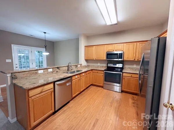 a kitchen with granite countertop stainless steel appliances cabinets a sink and a counter top space
