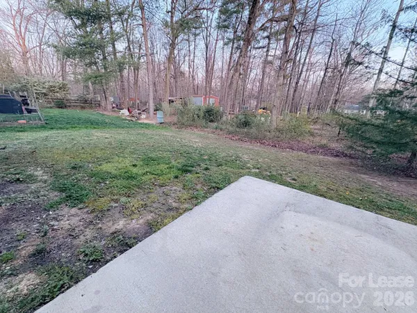 a view of a yard with trees plants and wooden fence