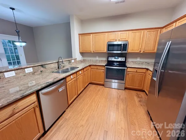 a kitchen with granite countertop a sink wooden floor and stainless steel appliances