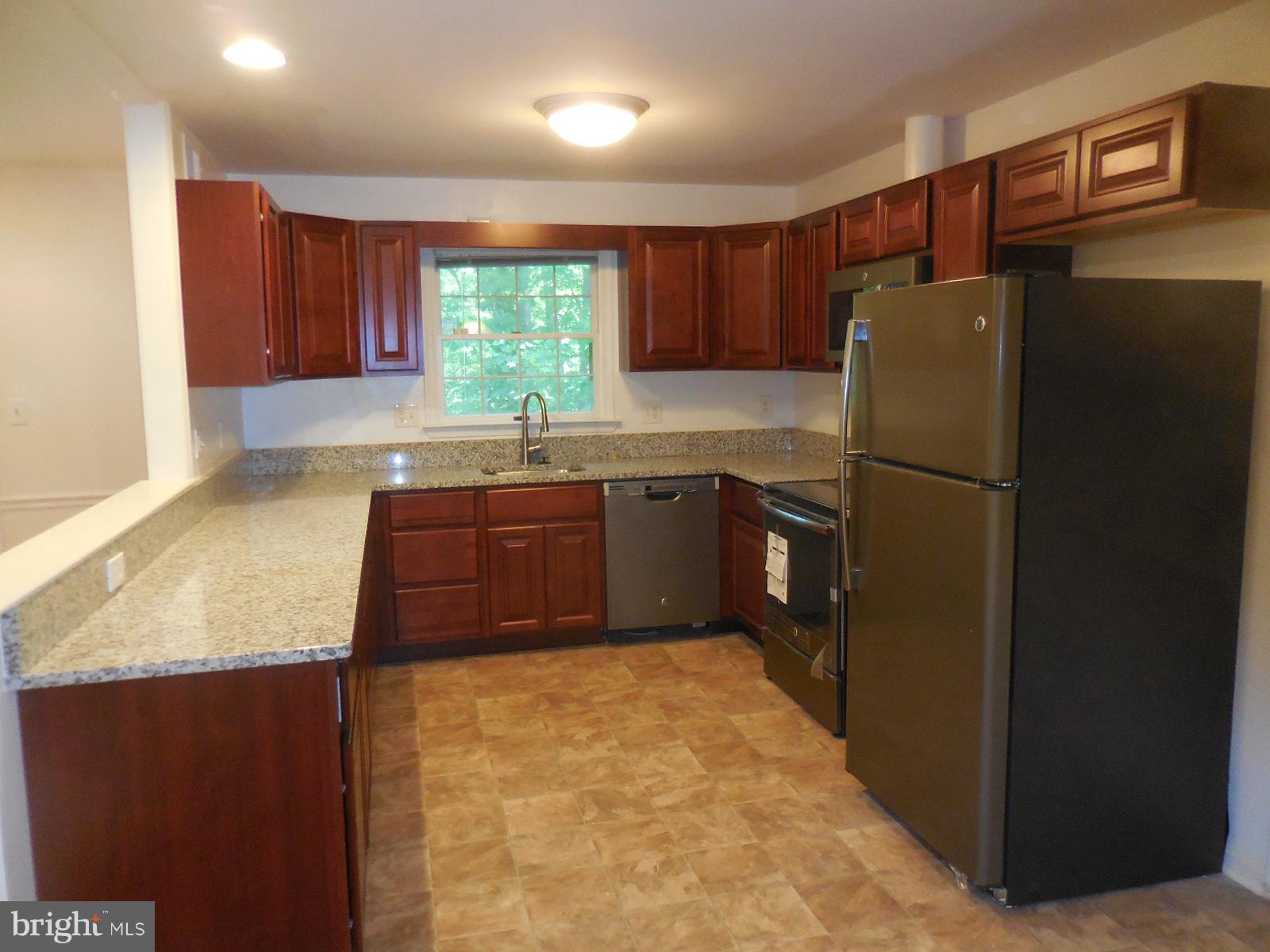 508 Holly Road Fort Washington, MD 20744 - Photo 3 of 29 a kitchen with stainless steel appliances granite countertop a refrigerator a sink dishwasher and wooden cabinets with wooden floor