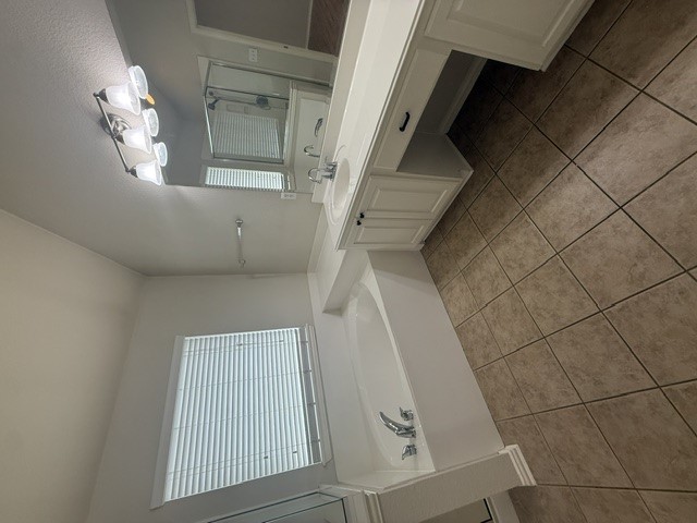 20724 Kearney Hill Road Pflugerville, TX 78660 - Photo 27 of 40 Bathroom featuring a built-in tub, dual vanity with integrated sink, wood-finish cabinetry, and tile flooring