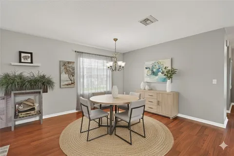 a dining room with furniture wooden floor a chandelier and a rug