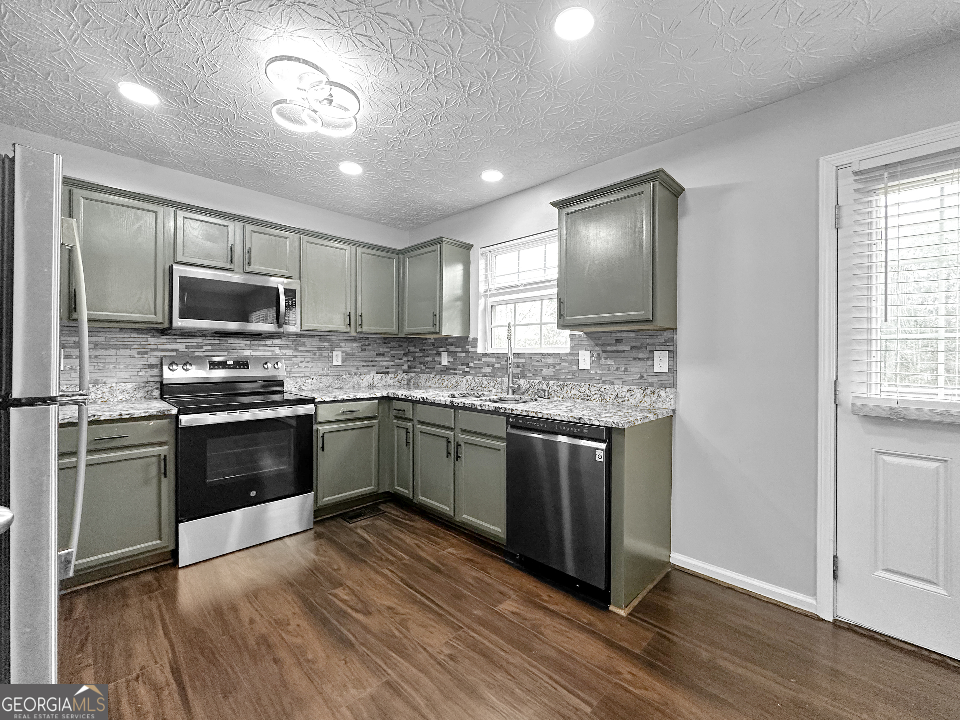 105 Aprils Way Union City, GA 30291 - Photo 7 of 20 a kitchen with granite countertop wooden floors stainless steel appliances and window