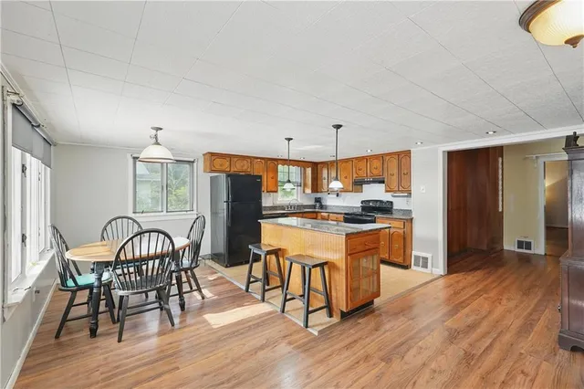 a kitchen with stainless steel appliances granite countertop a dining table chairs refrigerator sink and cabinets