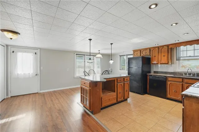 a kitchen with stainless steel appliances granite countertop a stove a refrigerator a sink dishwasher and wooden cabinets with wooden floor