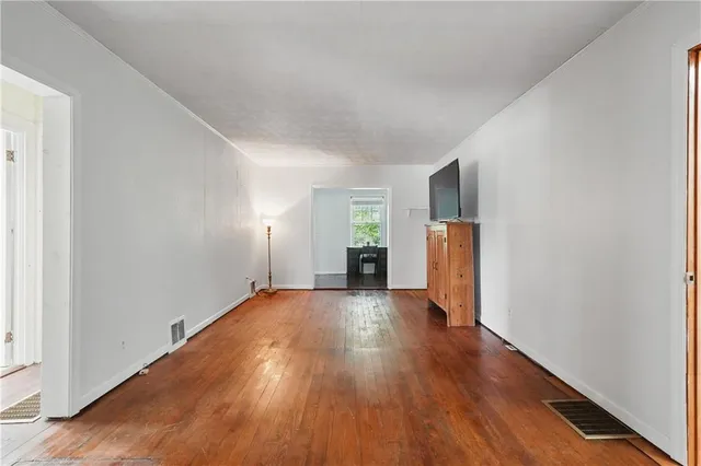 a view of a big room with wooden floor and windows