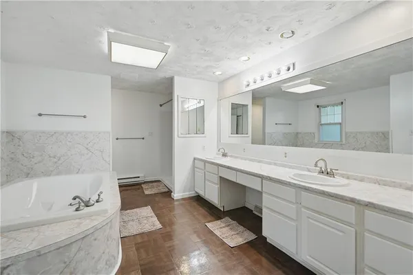 a spacious bathroom with a tub sink and mirror