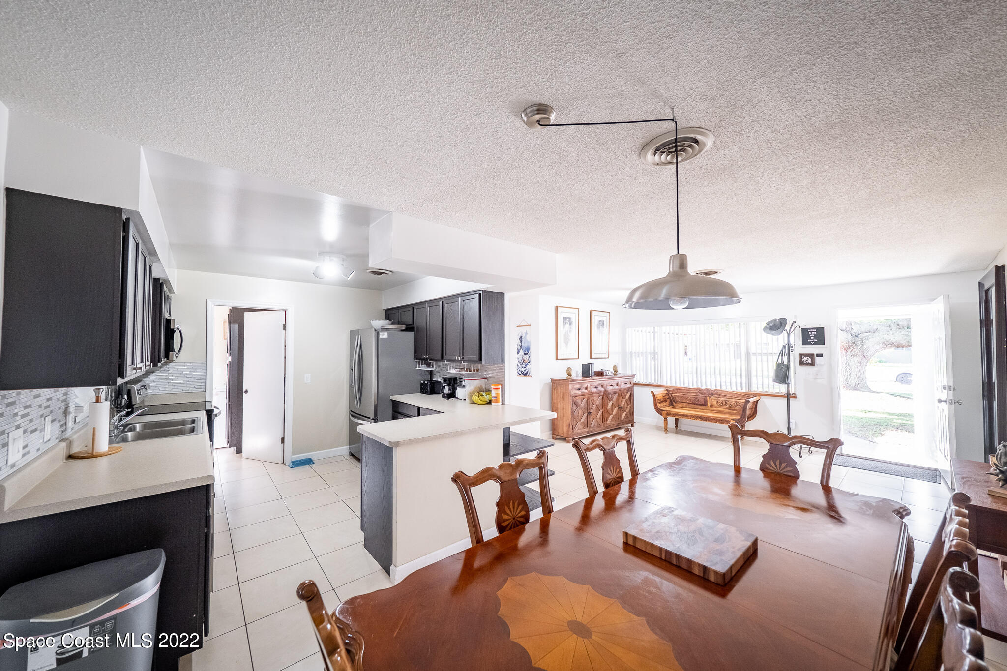 982 Cardon Drive Rockledge, FL 32955 - Photo 11 of 27 a living room with furniture a chandelier and a flat screen tv