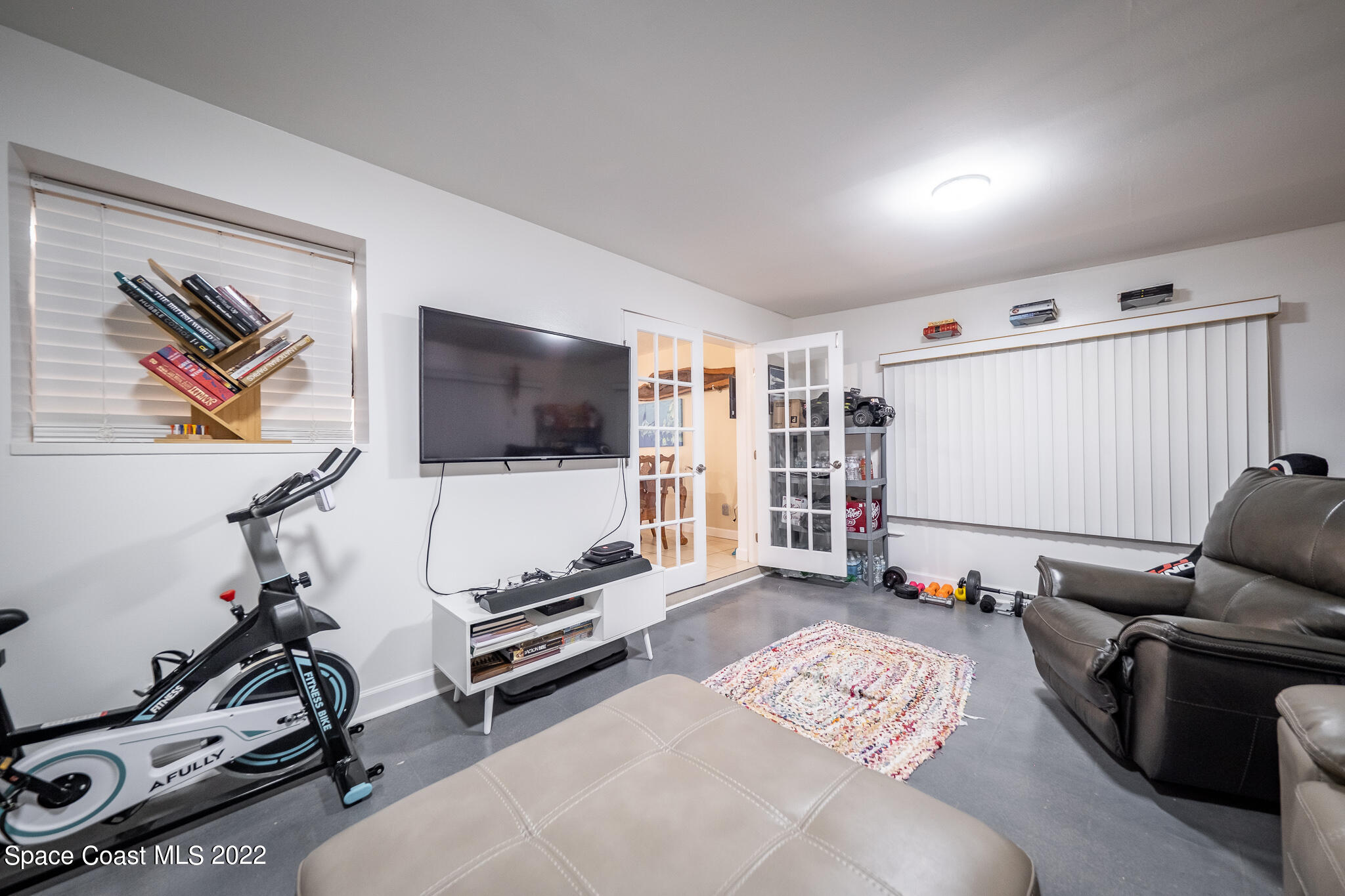 982 Cardon Drive Rockledge, FL 32955 - Photo 18 of 27 a living room with furniture gym equipment and a flat screen tv