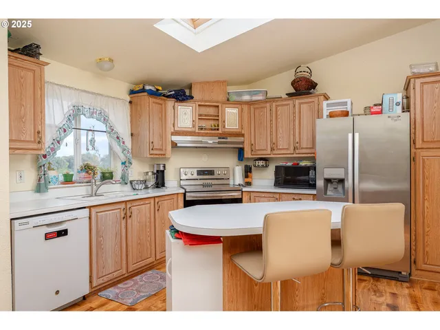 a kitchen with stainless steel appliances a refrigerator a stove a sink and white cabinets with wooden floor