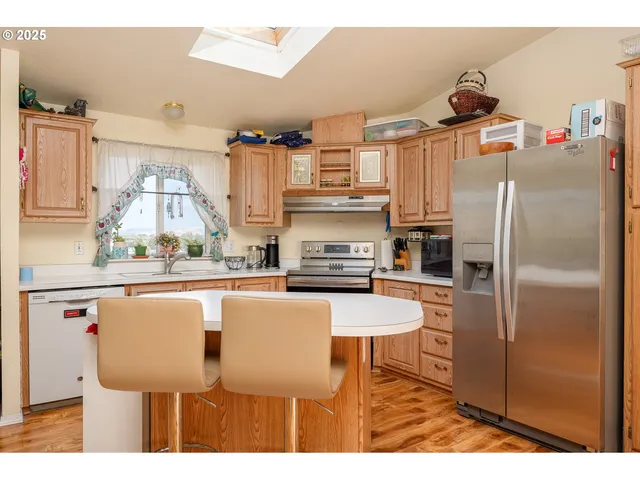 a kitchen with stainless steel appliances granite countertop a table chairs stove and refrigerator