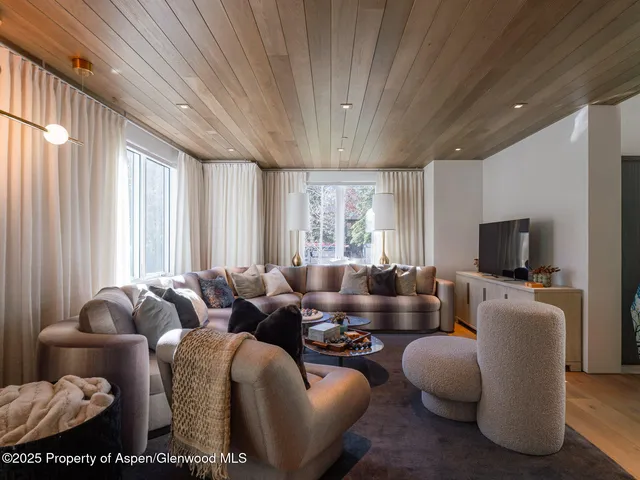 a living room with furniture a flat screen tv and a window