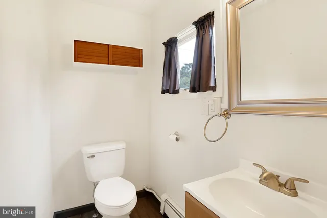 a bathroom with a toilet sink vanity and mirror