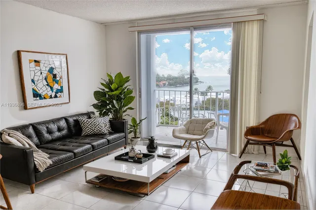 a living room with furniture and a large window with potted plants