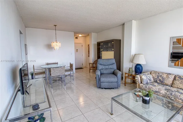 a living room with couches and kitchen view with wooden floor