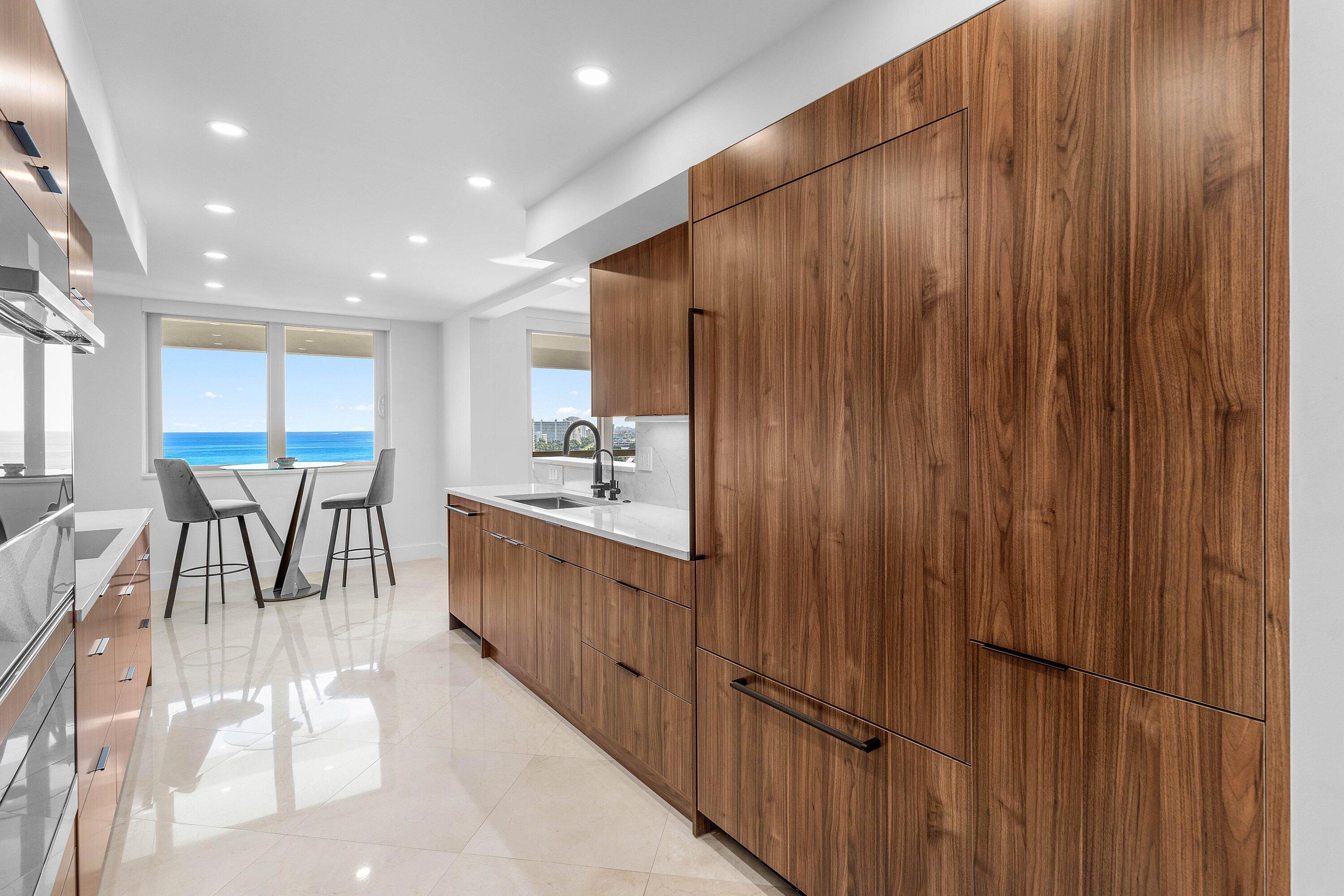 901 East Camino Real, Unit 15D Boca Raton, FL 33432 - Photo 14 of 42 a kitchen with kitchen island granite countertop wooden cabinets and stainless steel appliances