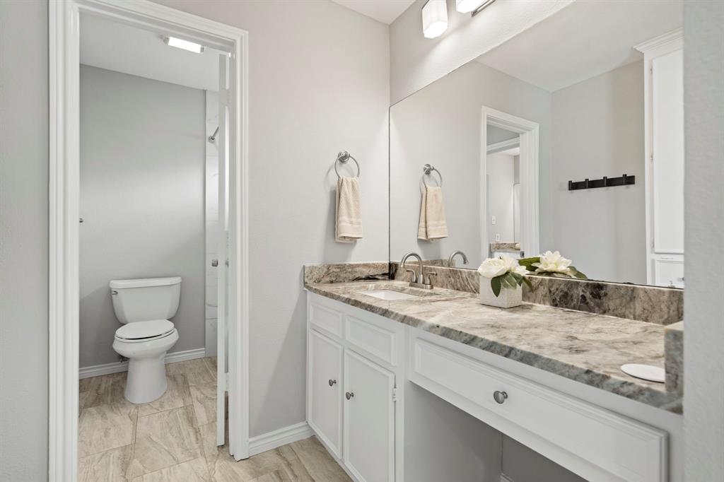 6349 Highgate Lane Dallas, TX 75214 - Photo 29 of 38 a bathroom with a granite countertop sink a toilet and a mirror