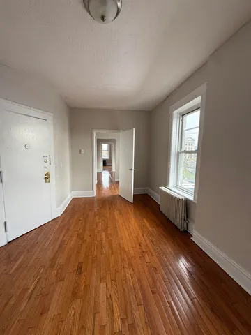 a view of empty room with wooden floor and fan