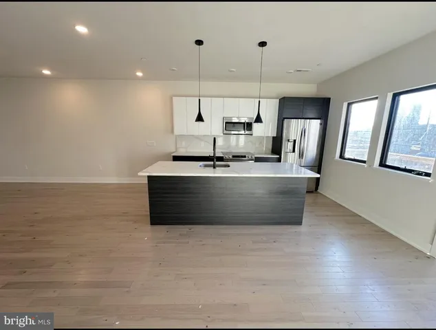 a large kitchen with stainless steel appliances a large counter top a stove a chimney a sink and a refrigerator