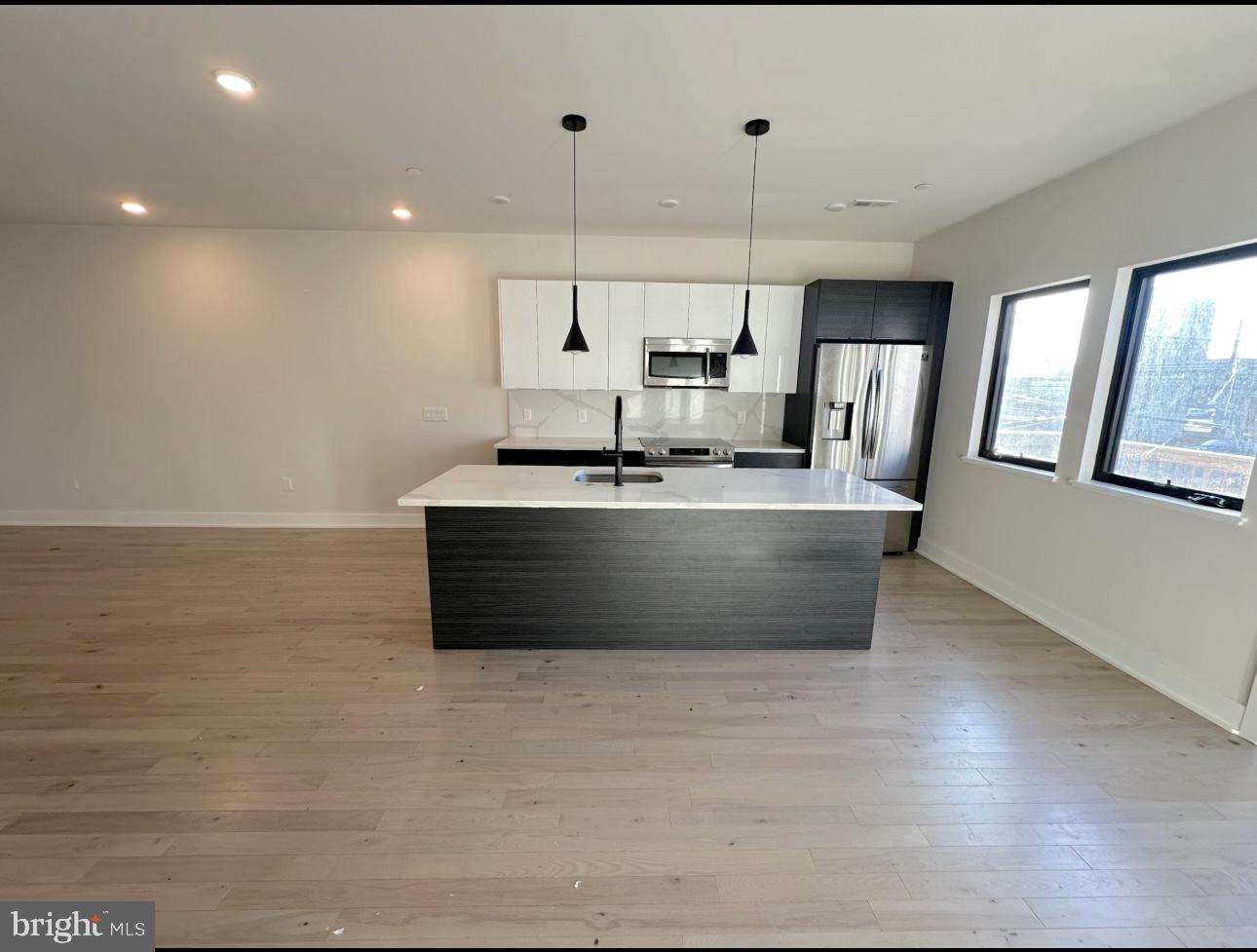 a large kitchen with stainless steel appliances a large counter top a stove a chimney a sink and a refrigerator