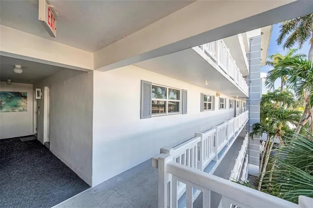 a front view of a multi story residential apartment building with a yard and plants