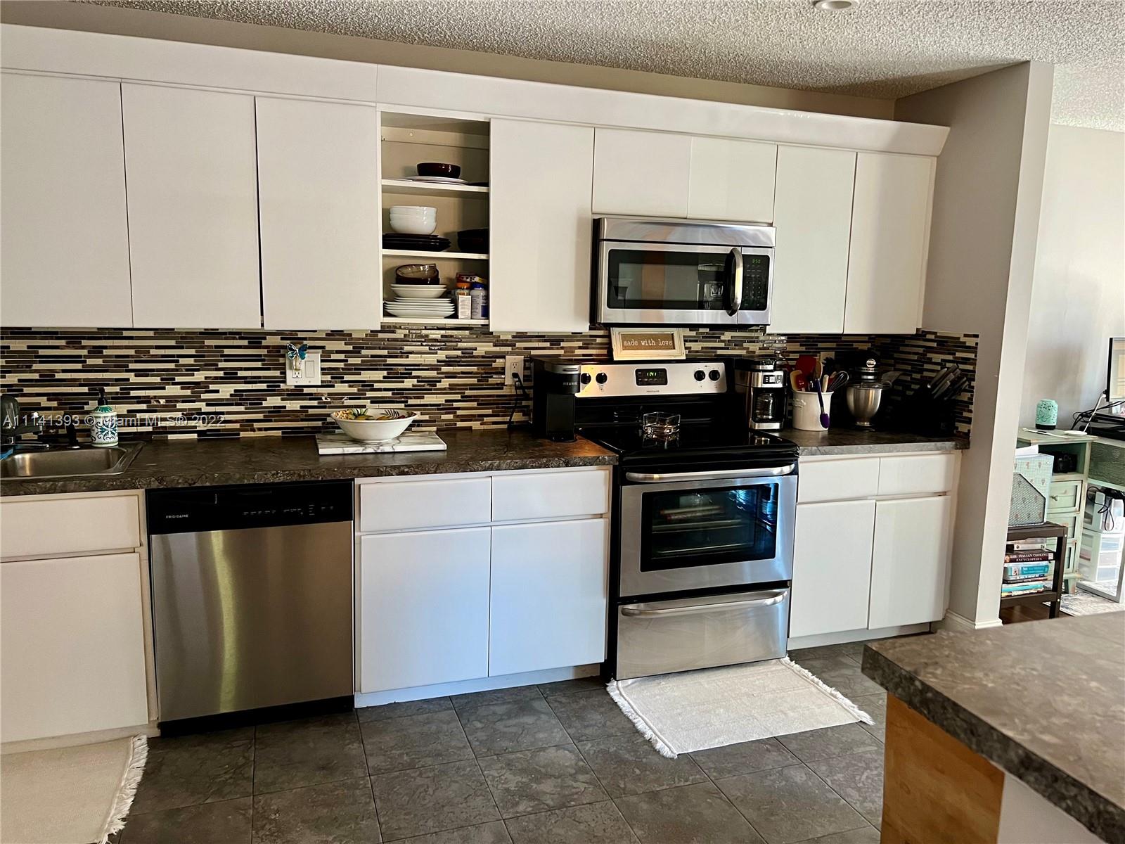 555 Racquet Club Road, Unit 25 Weston, FL 33326 - Photo 6 of 12 a kitchen with stainless steel appliances granite countertop a stove and a microwave