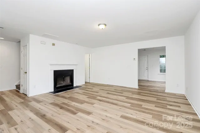 a view of empty room with wooden floor and fireplace