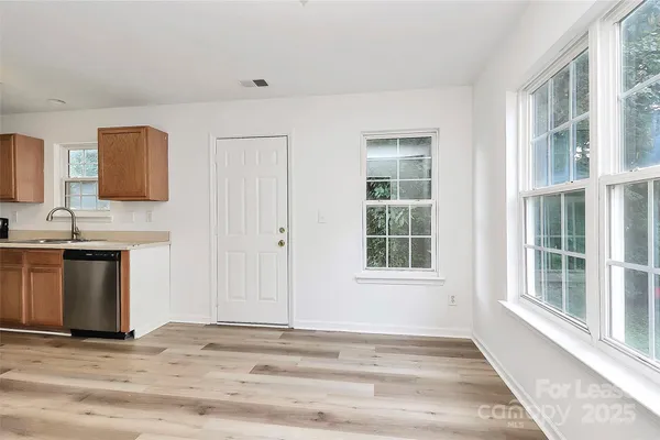 a view of an empty room with a window and a kitchen