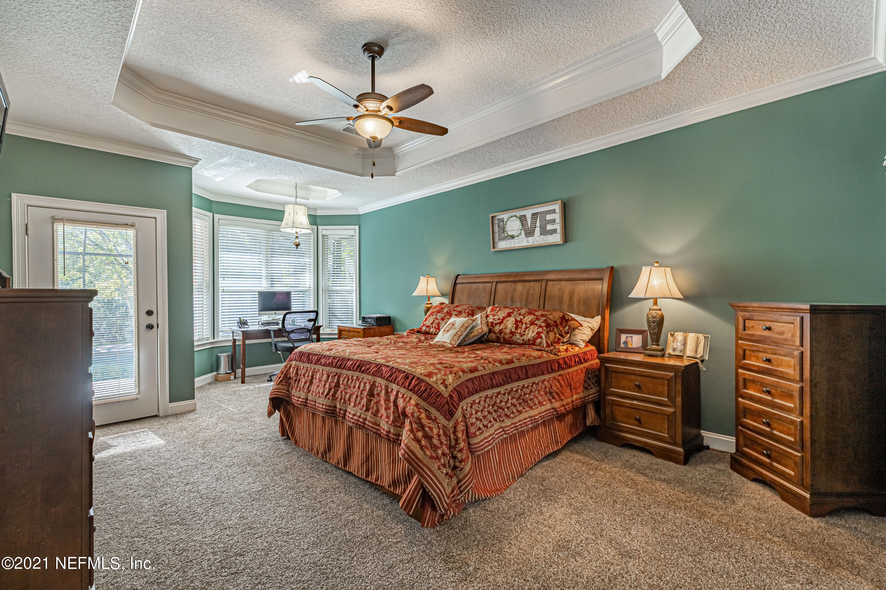 1827 Wild Grape Lane Fleming Island, FL 32003 - Photo 20 of 51 a bedroom with a bed and a chandelier