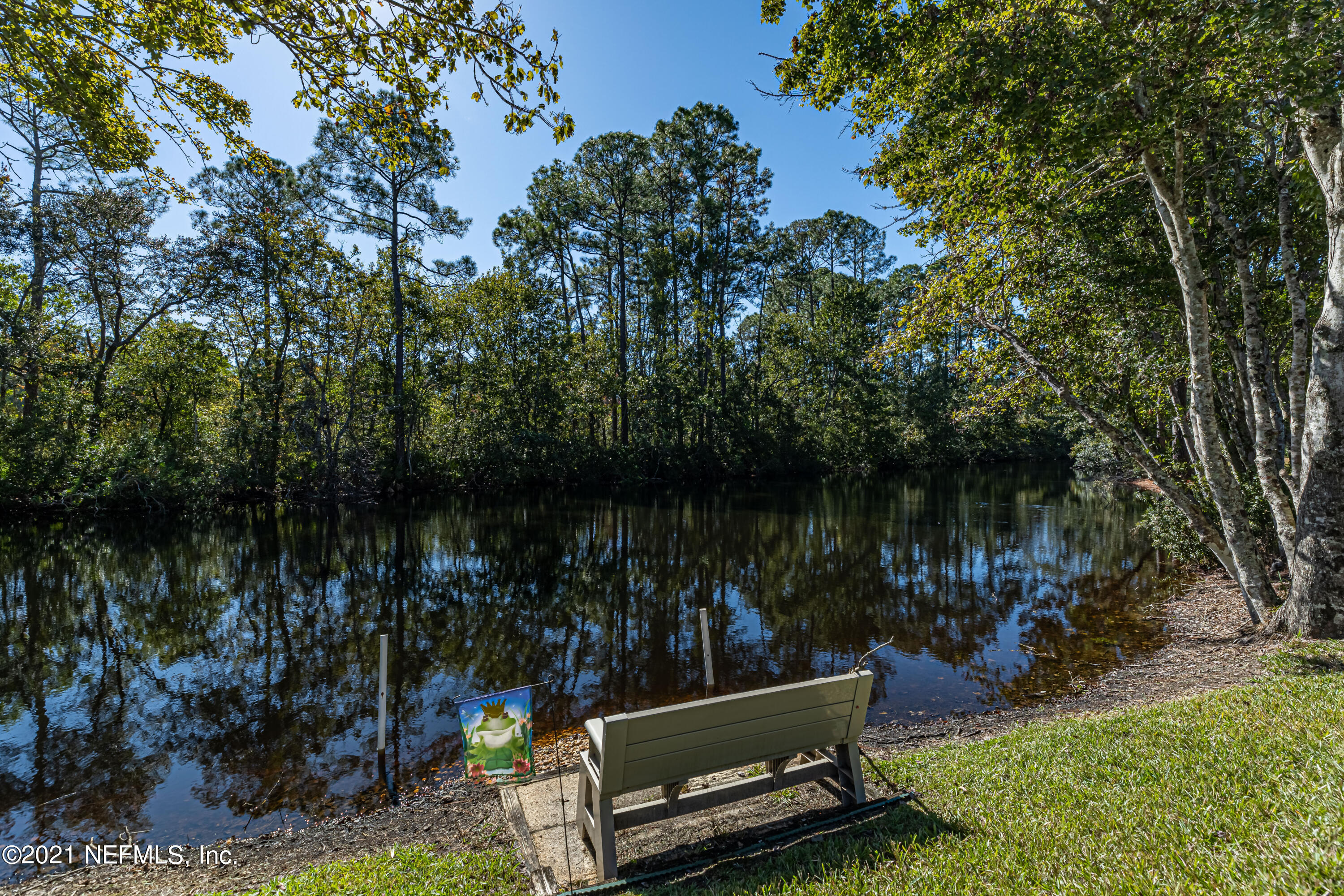 1827 Wild Grape Lane Fleming Island, FL 32003 - Photo 41 of 51 a view of a lake with a bench and a trees