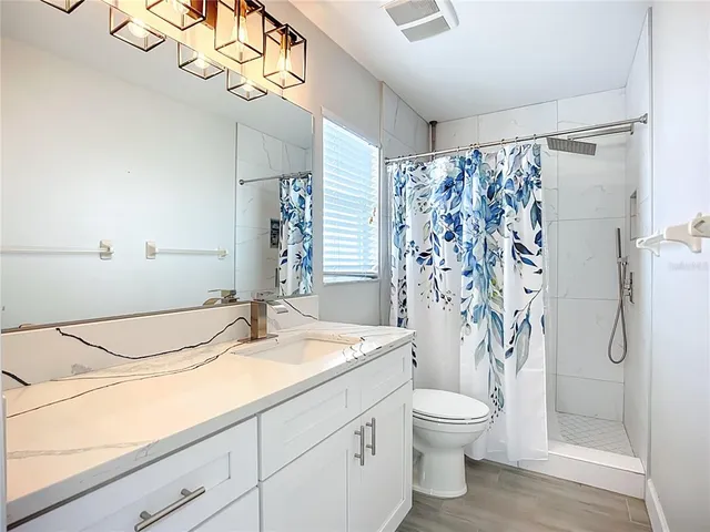 a bathroom with a granite countertop sink a toilet and shower curtain