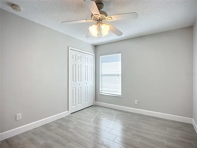 an empty room with chandelier fan and windows