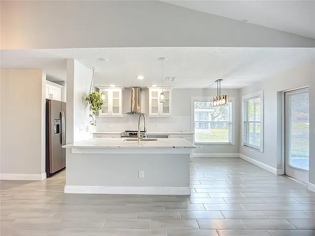 a large kitchen with stainless steel appliances a large counter top a stove and a refrigerator