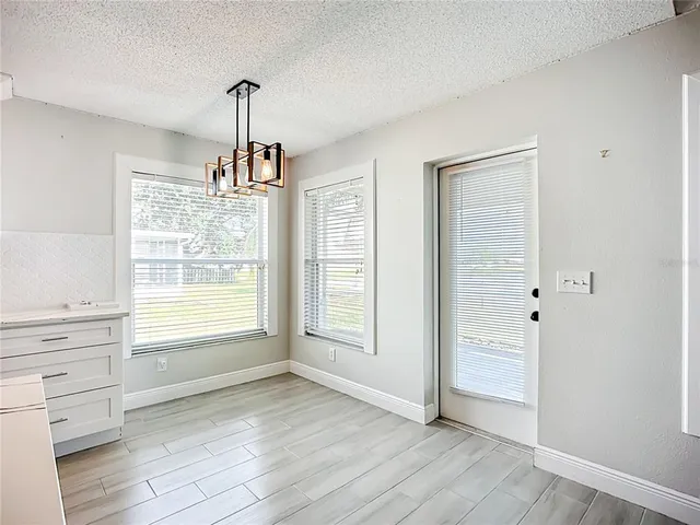 an empty room with wooden floor cabinet and windows