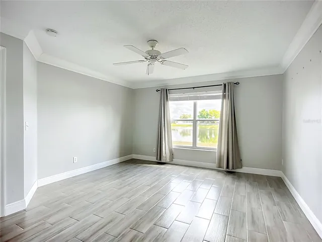 a view of empty room with wooden floor and fan