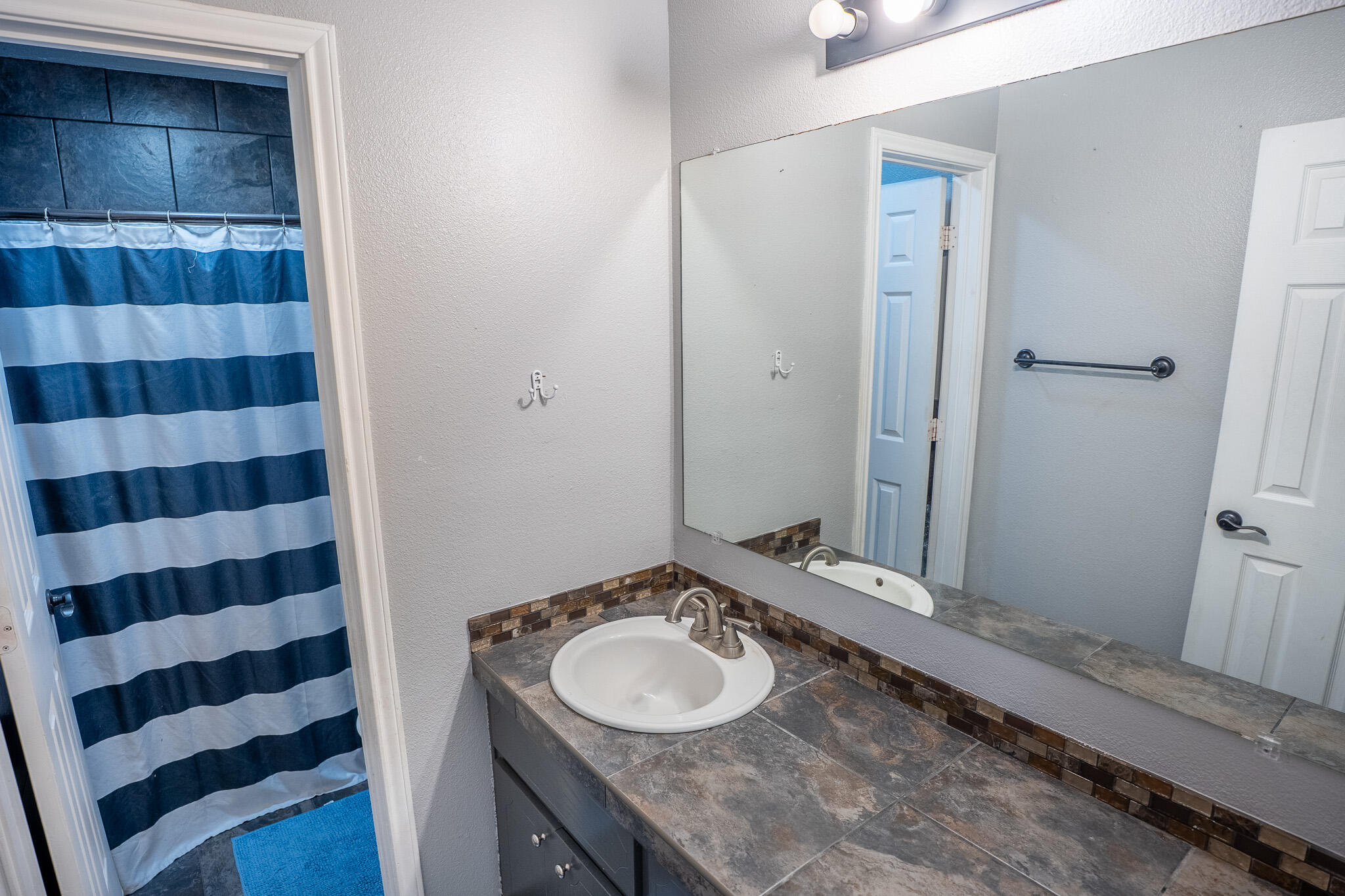 1609 78th Street Lubbock, TX 79423 - Photo 28 of 36 a bathroom with a granite countertop sink and a mirror