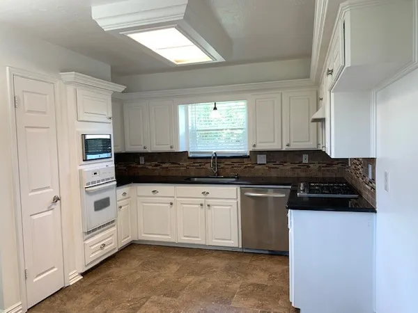 a kitchen with granite countertop white cabinets and white appliances