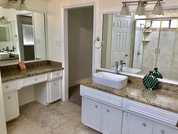 a bathroom with double vanity sinks a granite counter top and a granite top
